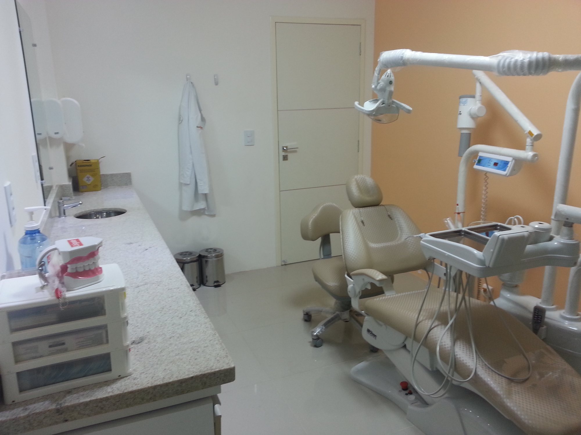 Consultório da Oral Prime com cadeira odontológica e parede laranja